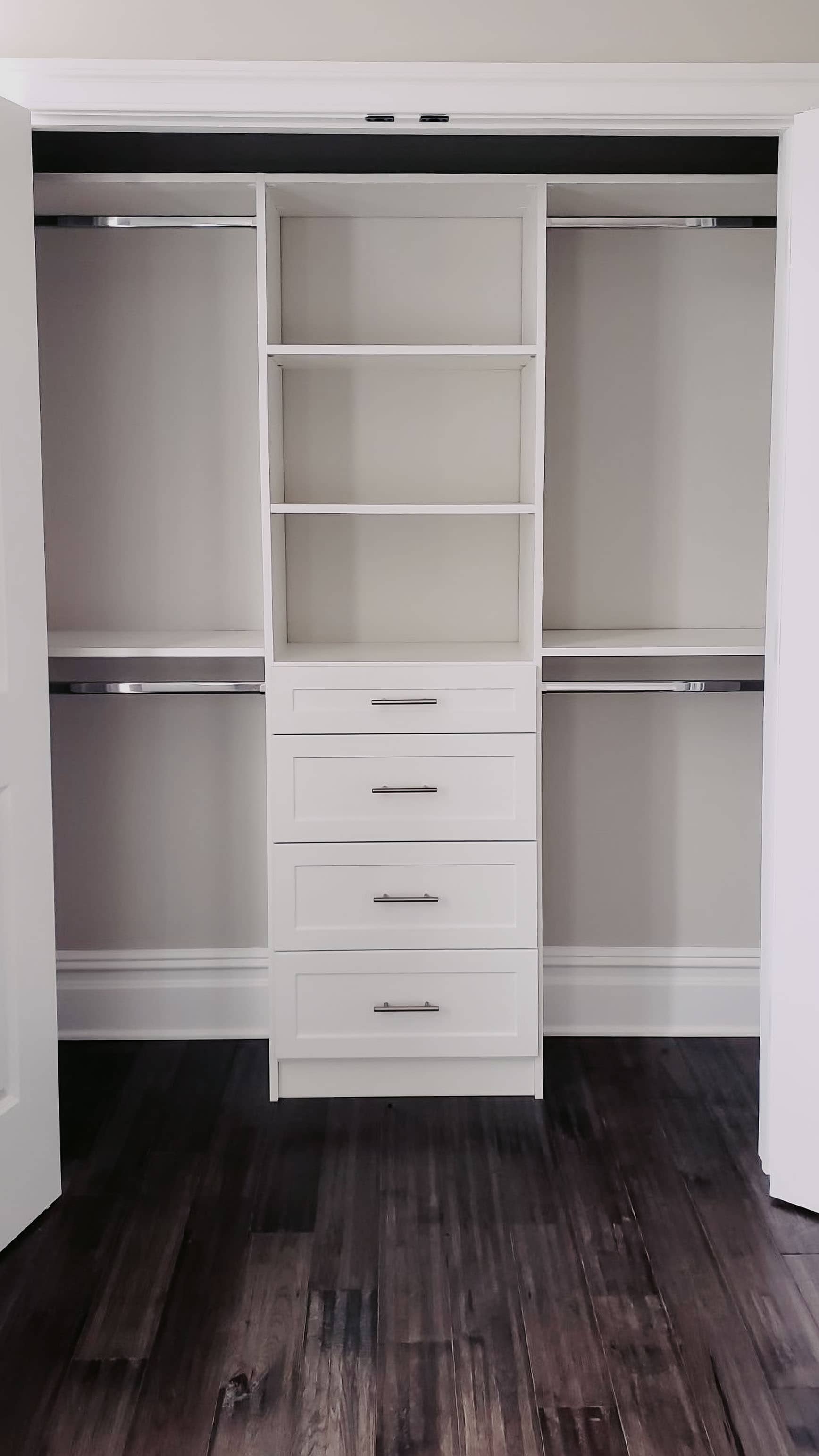 Custom walk-in closet with white built-in shelving, drawers, and hanging rods by GM Cabinetry in Georgia