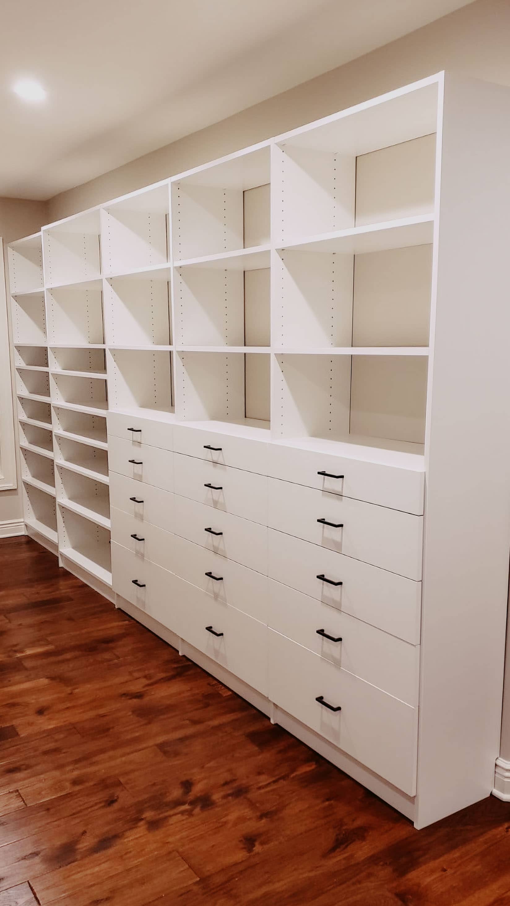 Large custom closet wall system with white cubby shelving, shoe storage, and built-in drawers