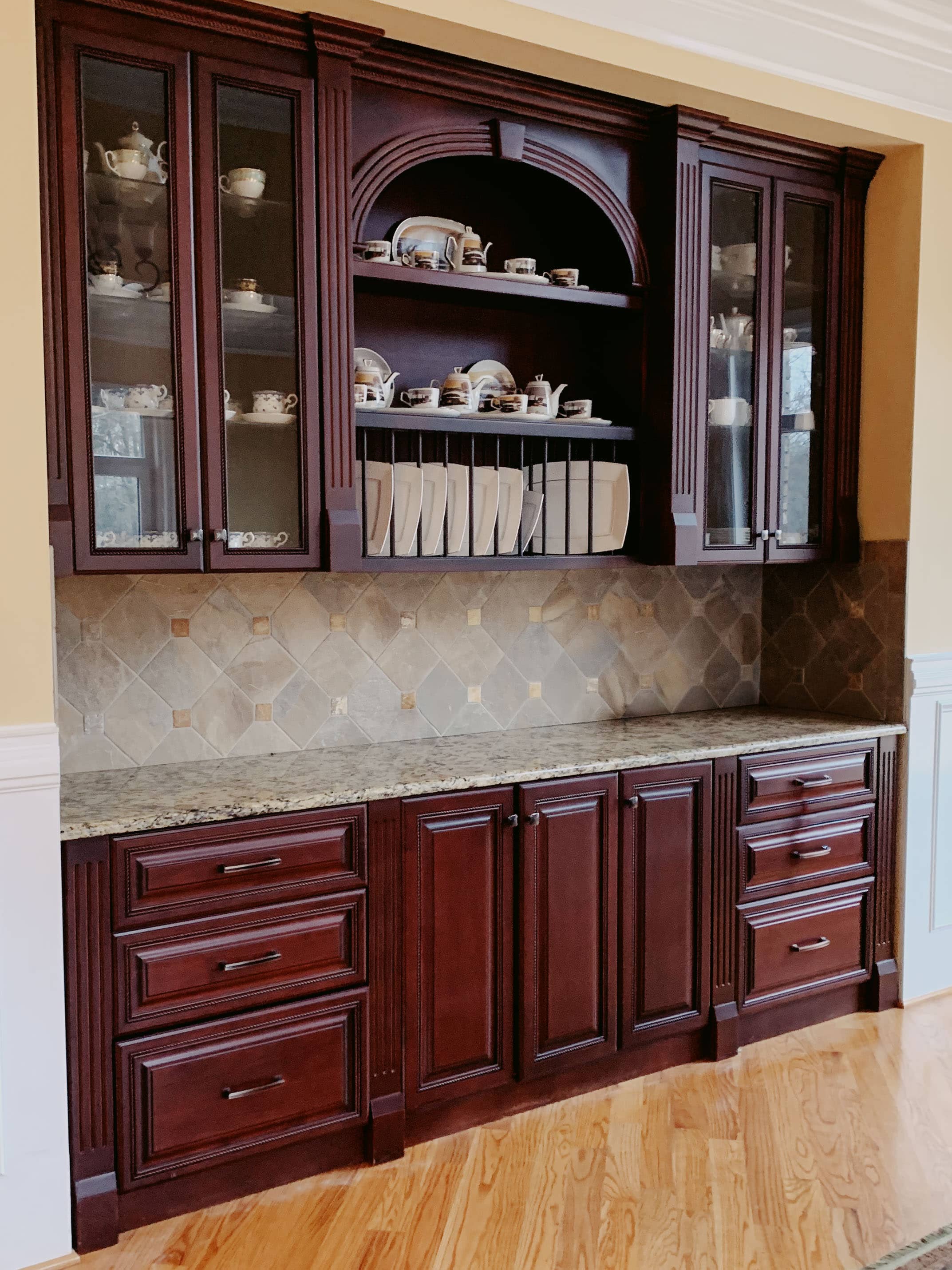 Custom china cabinet built into kitchen with glass-front upper doors and closed lower storage by GM Cabinetry