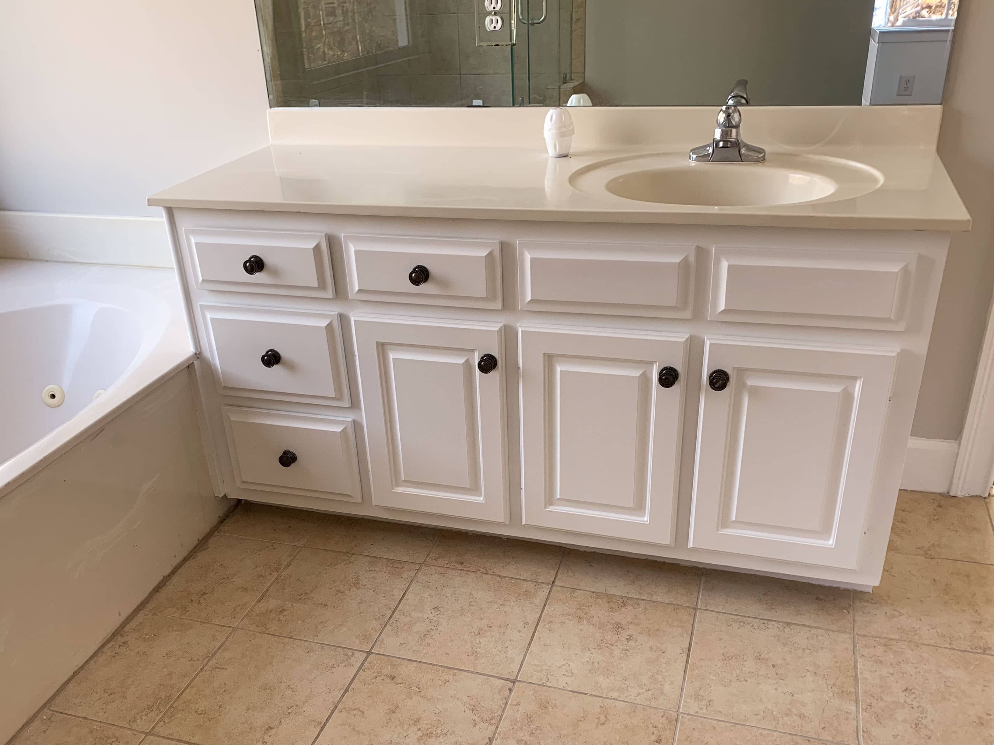 Completed custom bathroom vanity installation with white cabinet doors and chrome hardware by GM Cabinetry
